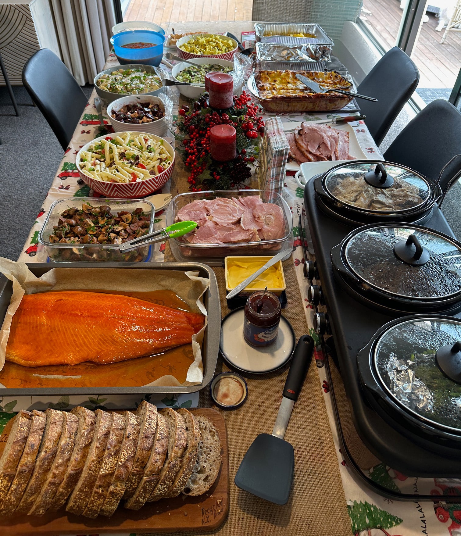 An array of colourful dishes at a Kiwi Christmas BBQ showcasing 'bring a plate' culture, with salads, salmon, ham, and other festive foods spread across a shared table.